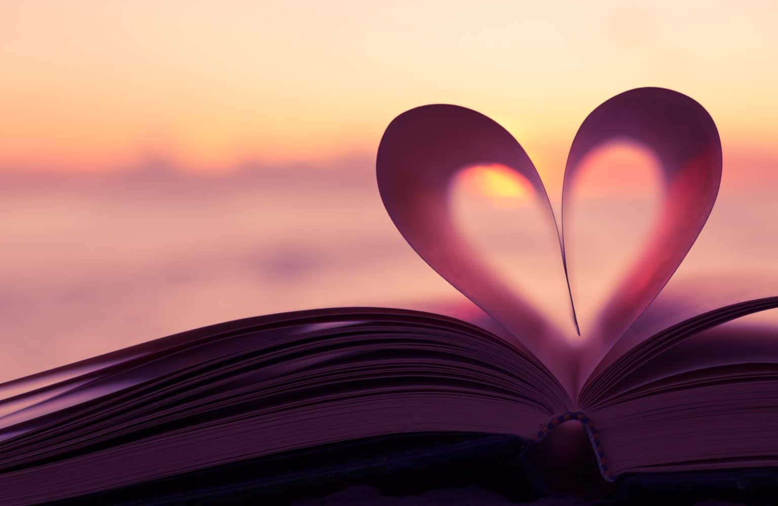 a book of pages formed into a heart set in front of a soft background and in pink tones.