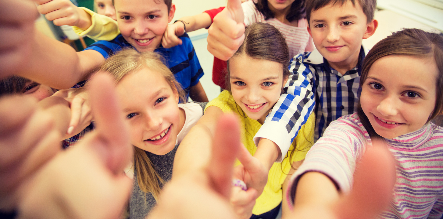 A group of school kids showing thumbs up at school