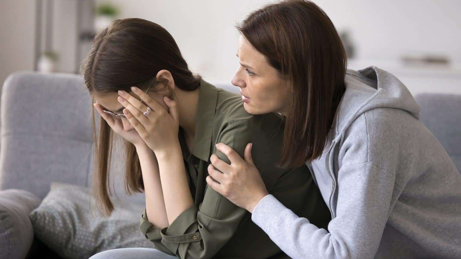 Concerned middle aged mother calms crying teen daughter during an argument