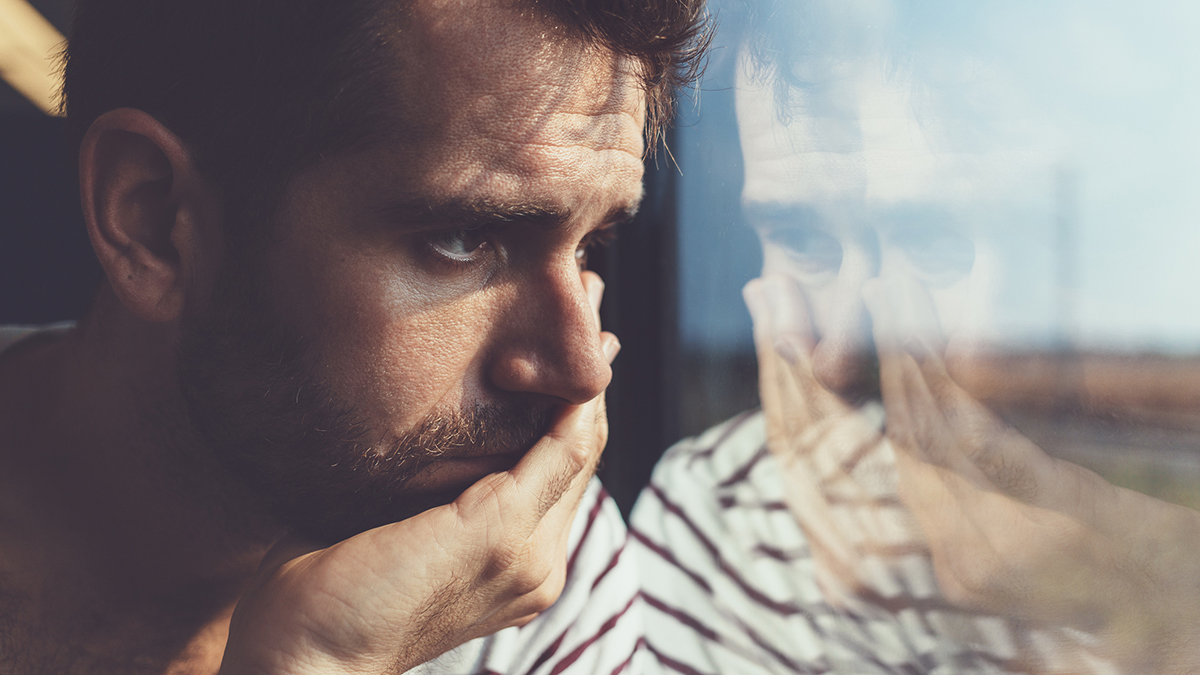 Sad young man with a shattered heart looking through the window
