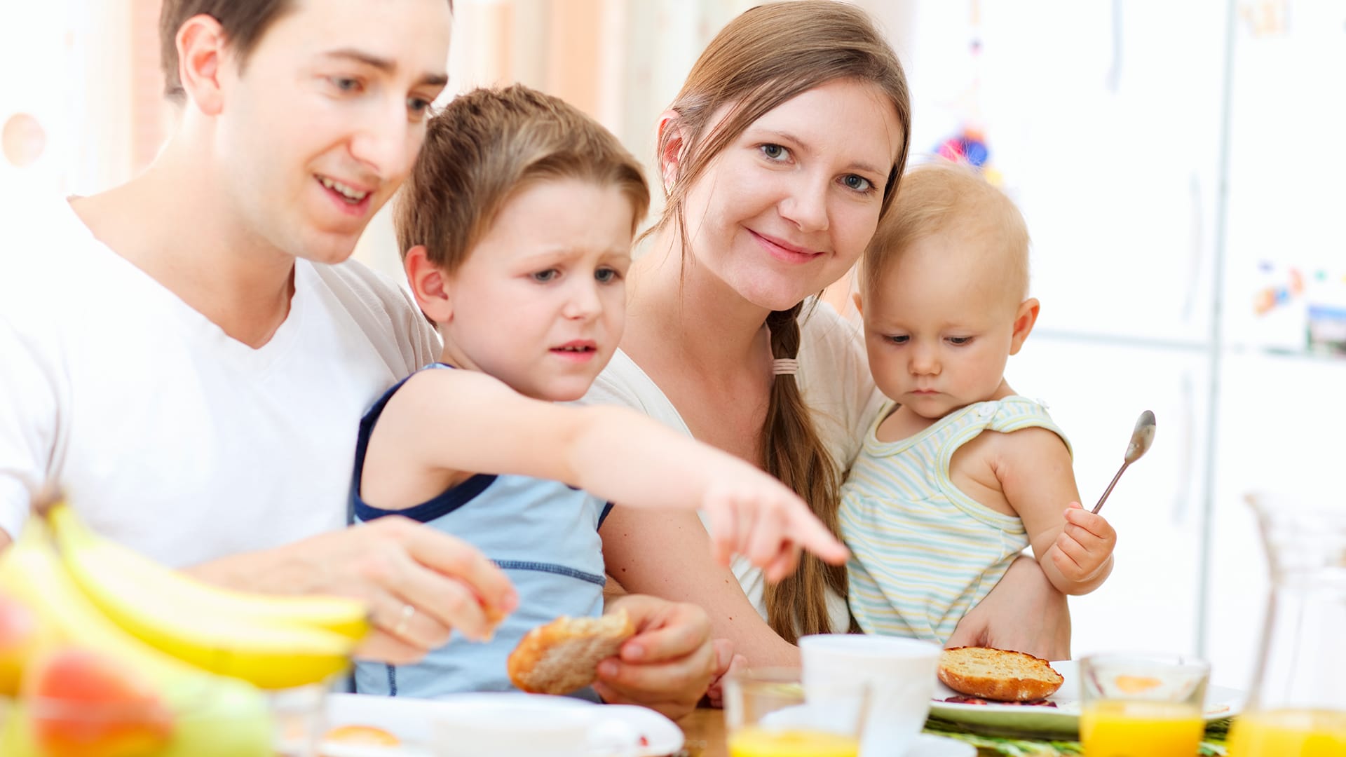 A young family - husband, wife young toddler and baby having brunch.