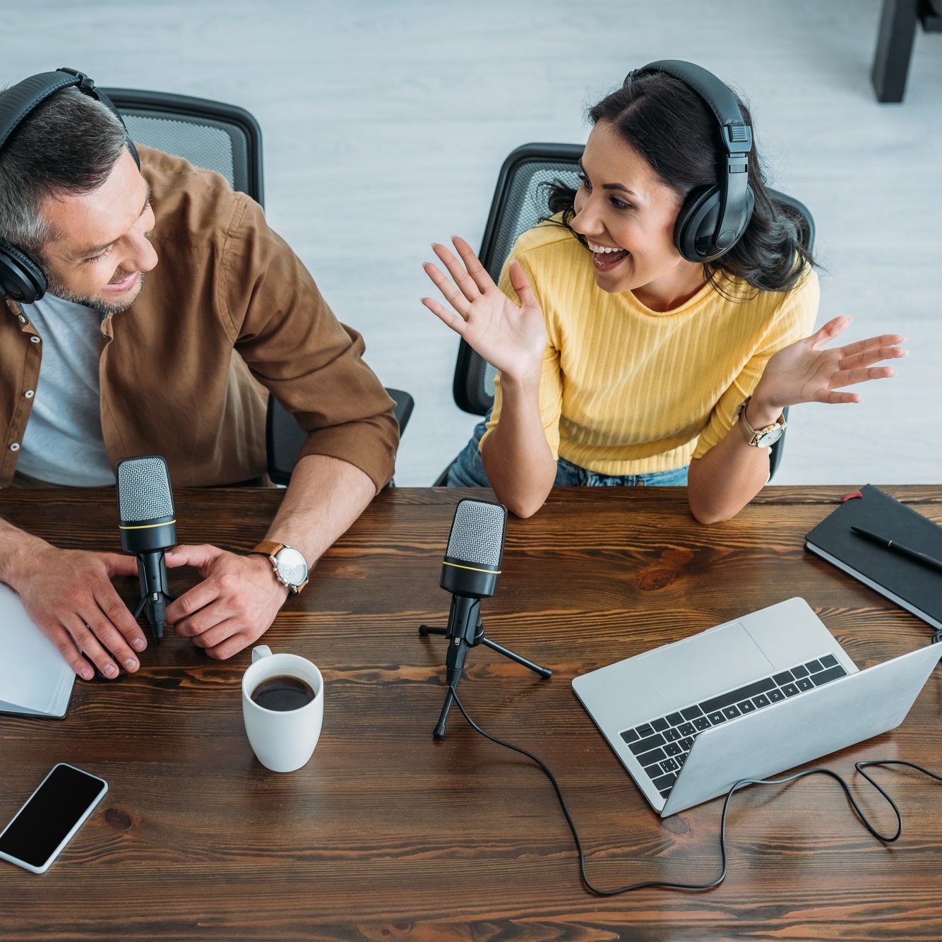 overhead of two cheerful radio hosts recording podcast in radio studio